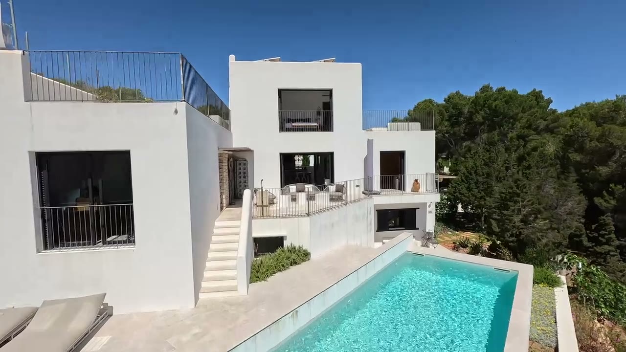 Vuelo exterior sobre una villa blanca de arquitectura moderna con piscina, grabado con dron por Aeroflow Studio